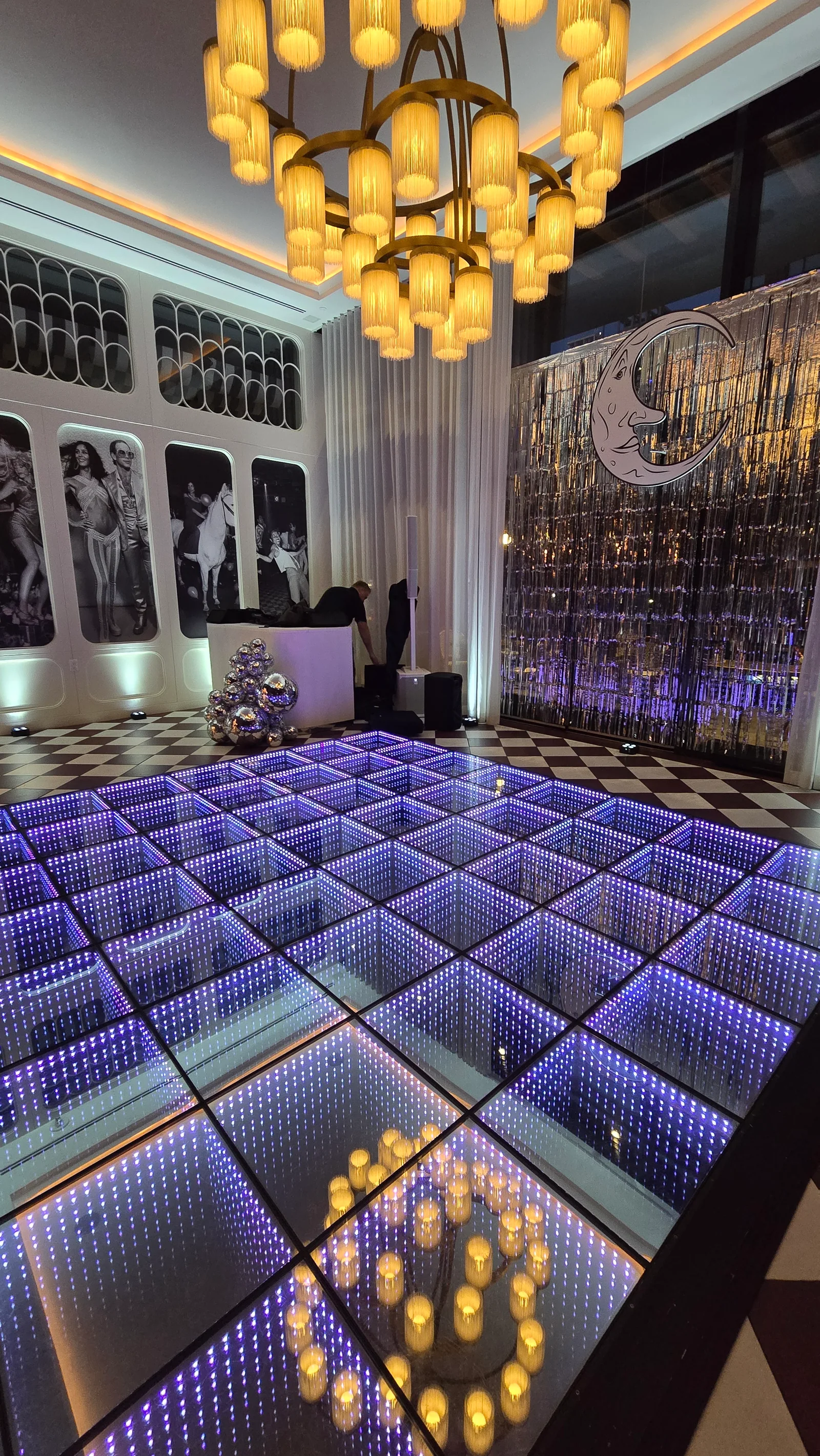 Blue infinity LED dance floor beneath chandeliers and an art-deco moon backdrop