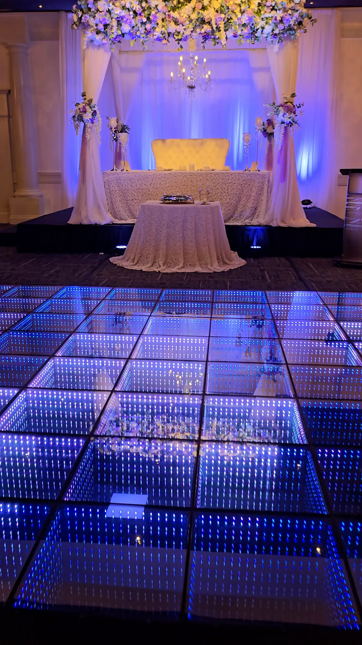 Blue infinity LED dance floor in front of a wedding sweetheart table