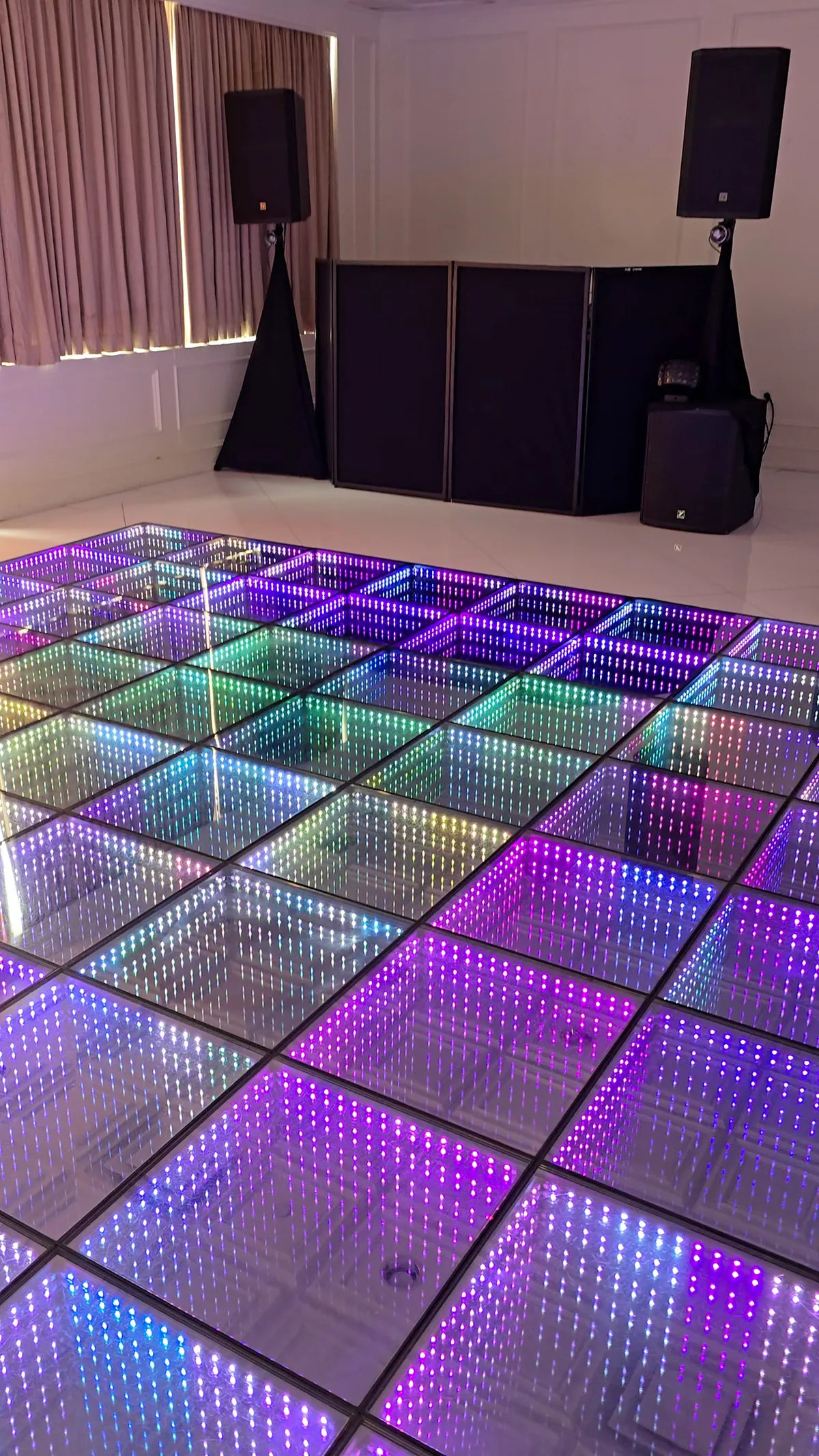 Full-color infinity LED dance floor installed beside a DJ booth