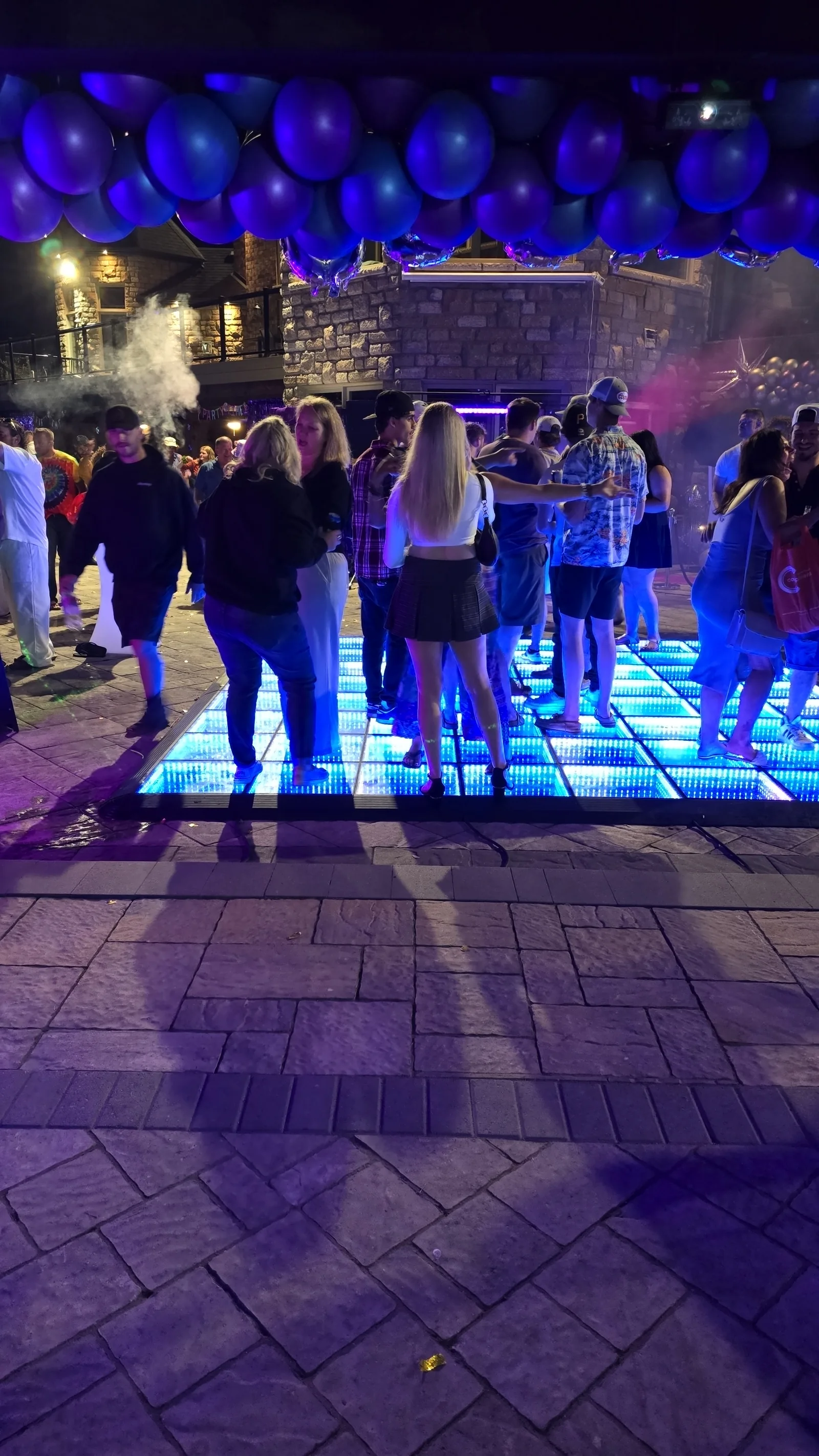 Blue infinity LED dance floor filled with guests at an evening celebration