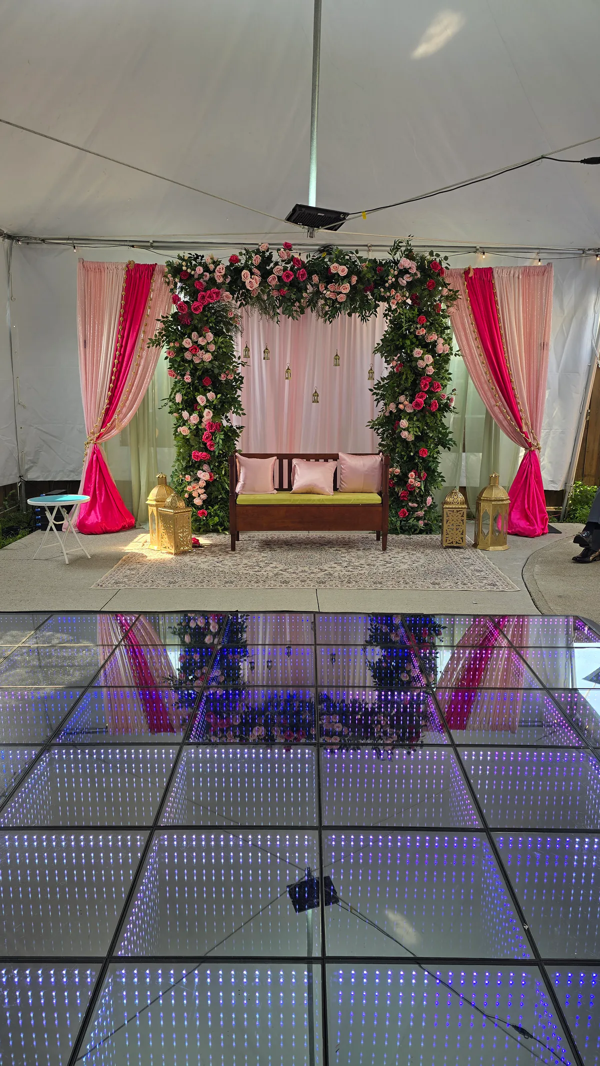 Infinity LED floor aligned with a floral wedding backdrop inside a tent