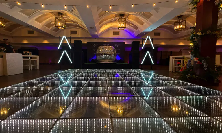 Large infinity LED dance floor centered in a vaulted ballroom